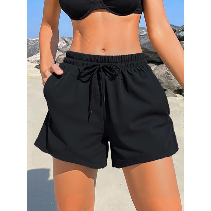 Bekväma dambadshorts med mjuk elastisk midja och praktiska fickor, perfekta för avkoppling och sommarlek.