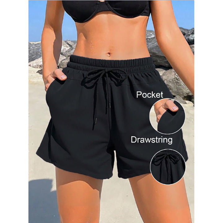 Svarta sportiga dambadshorts med justerbar elastisk midja, perfekta för aktiva sommardagar vid havet.