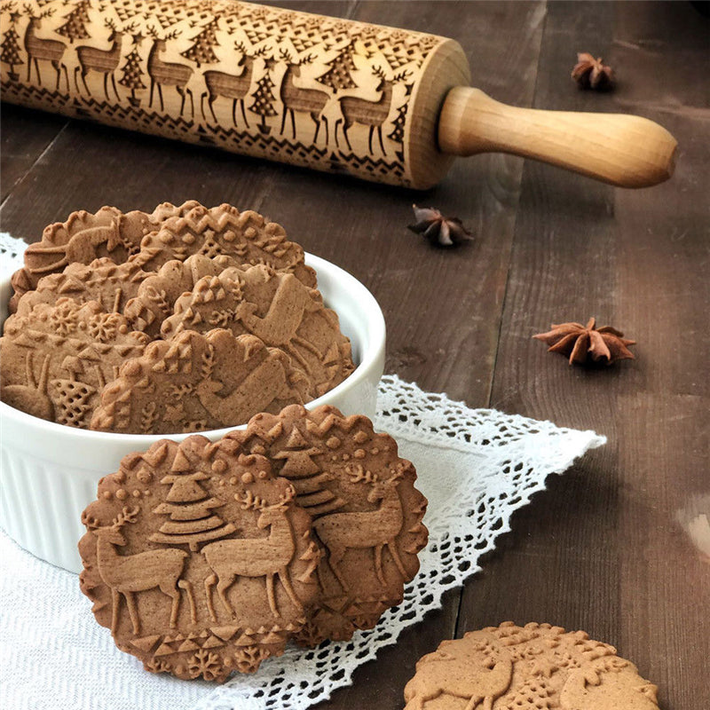 Träkavel med renmotiv som rullas över hembakade kakor