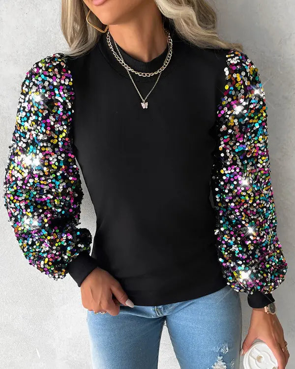 Kvinna i svart blus med färggranna paljettärmar och jeans
