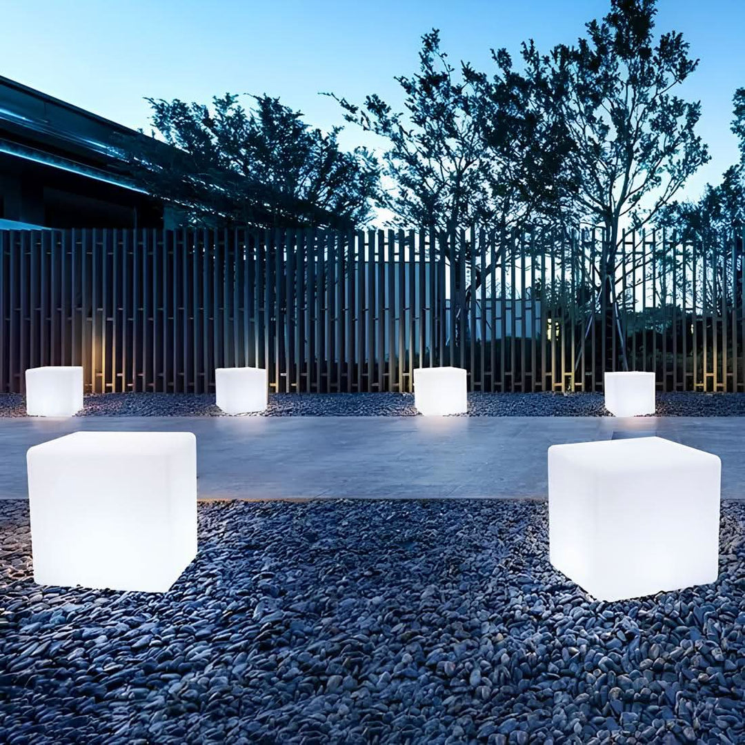 Flera kubformade LED-lampor placerade längs med en stenlagd uteplats