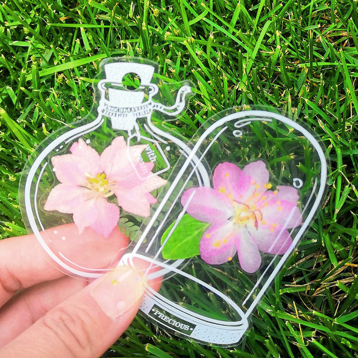 "Transparent bokmärke med torkade blommor, handgjord, elegant design, tunt och hållbart; perfekt för bokälskare."