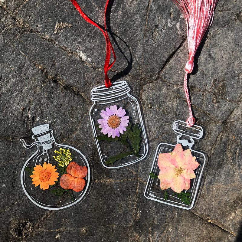"Transparent bokmärke med torkade blommor, handgjord, elegant design, tunt och hållbart; perfekt för bokälskare."