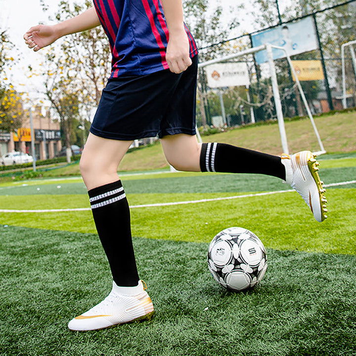 Framifrån av de professionella unisex fotbollsskorna i guld färg, redo för spel.