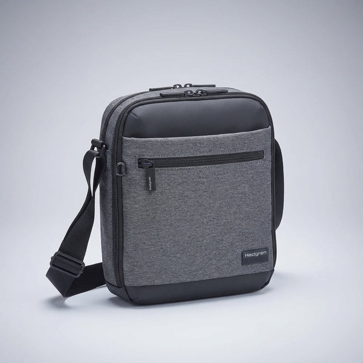 Person bär en svart unisex messengerväska (crossbody) som en praktisk vardags- eller resväska.