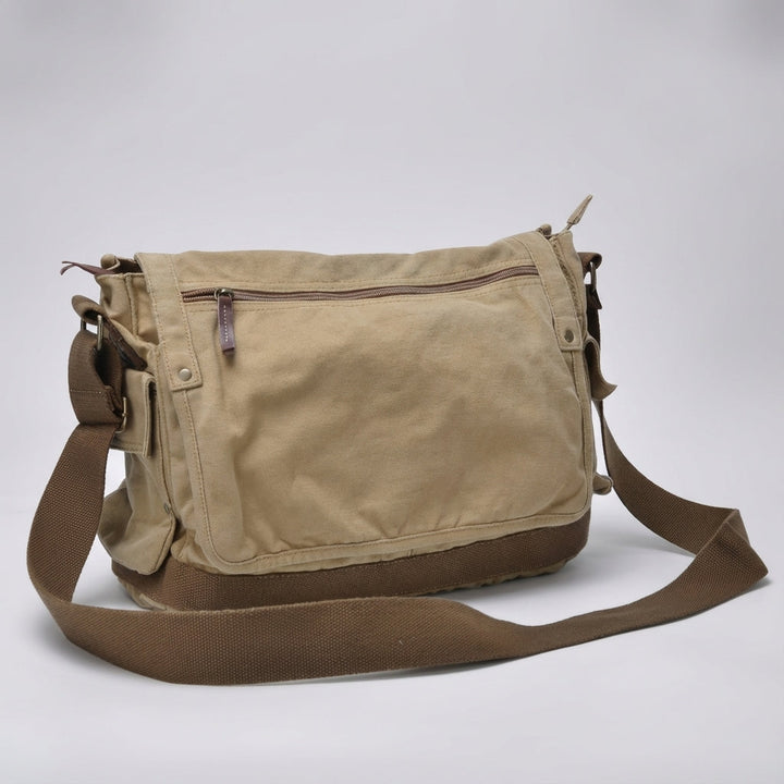 Öppen vintage canvas messengerväska visar organiserad insida med fack för laptop och tillbehör.