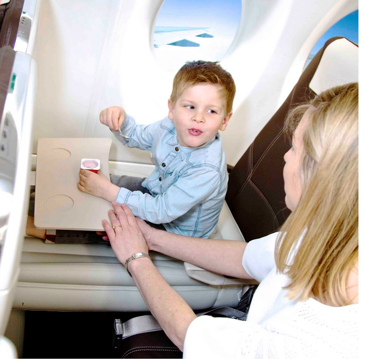 Mamma och barn som äter och myser på den uppblåsbara flygplanssängen ombord