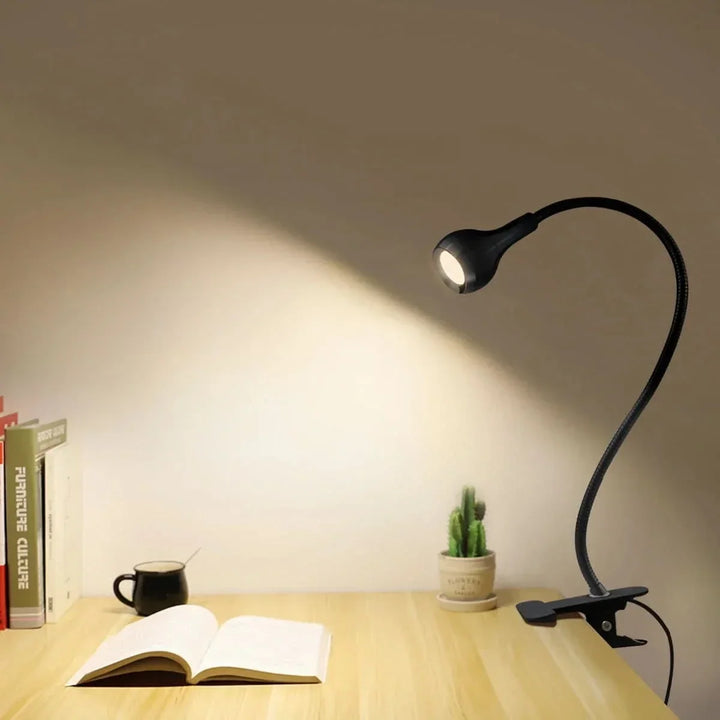 Svart USB-driven LED-läslampa med varmvitt ljus bredvid böcker