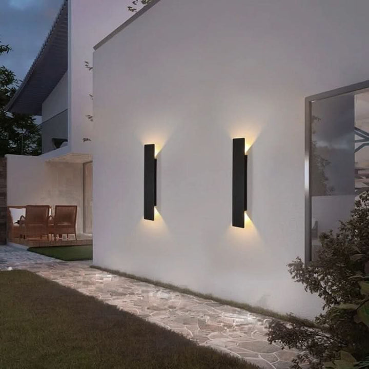 Svart modern LED-utomhusvägglampa monterad på vit husfasad
