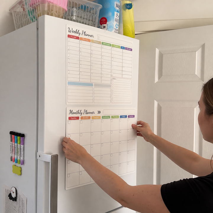 Person som sätter upp en månadskalender med magnet på kylskåpet