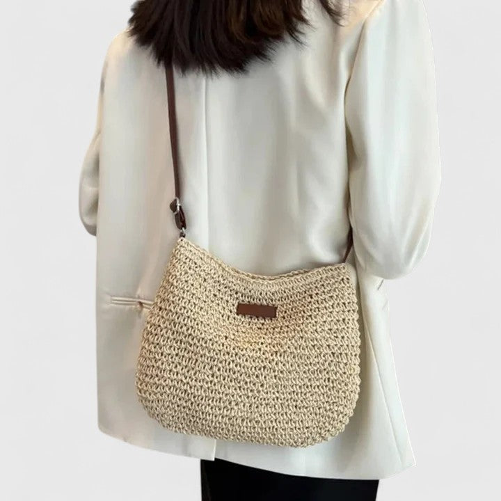Damaccessoar i form av en moderiktig khaki väska mot neutral bakgrund