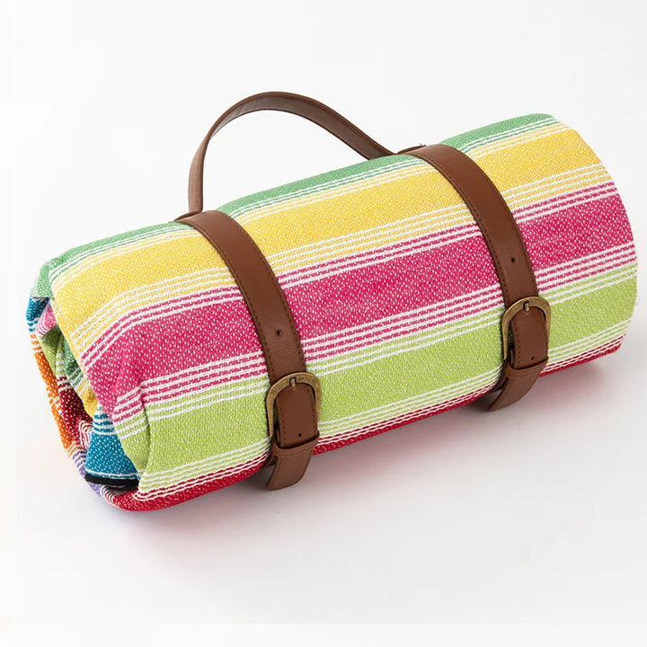 Smidig picknickfilt hoprullad med praktisk bärrem för enkel transport.
