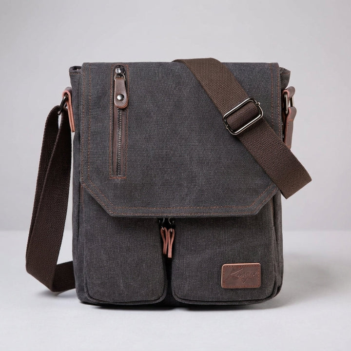 Man bär en snygg vintage messenger-väska i canvas. Mörkbrun axelväska med robust design för stadsliv.