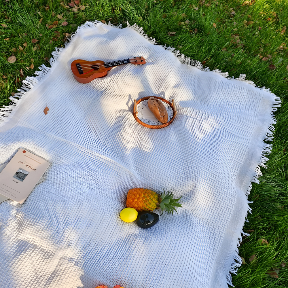 Elegant vit boho filt med dekorativa tofsar, perfekt som utomhusfilt för picknick och trädgårdsfester.