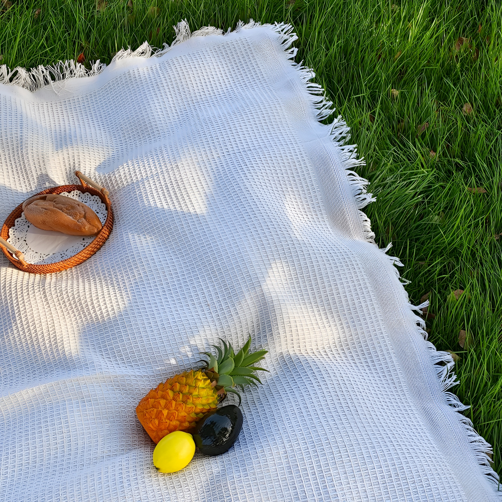 Mysig vit picknickfilt med tofsar för avkoppling utomhus, passar som trädgårds- eller strandfilt.