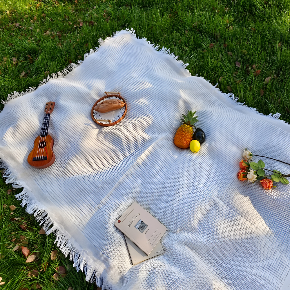 Vit filt med tofsar, idealisk som picknickfilt, strandfilt eller campingfilt. Boho-stil för uteliv.