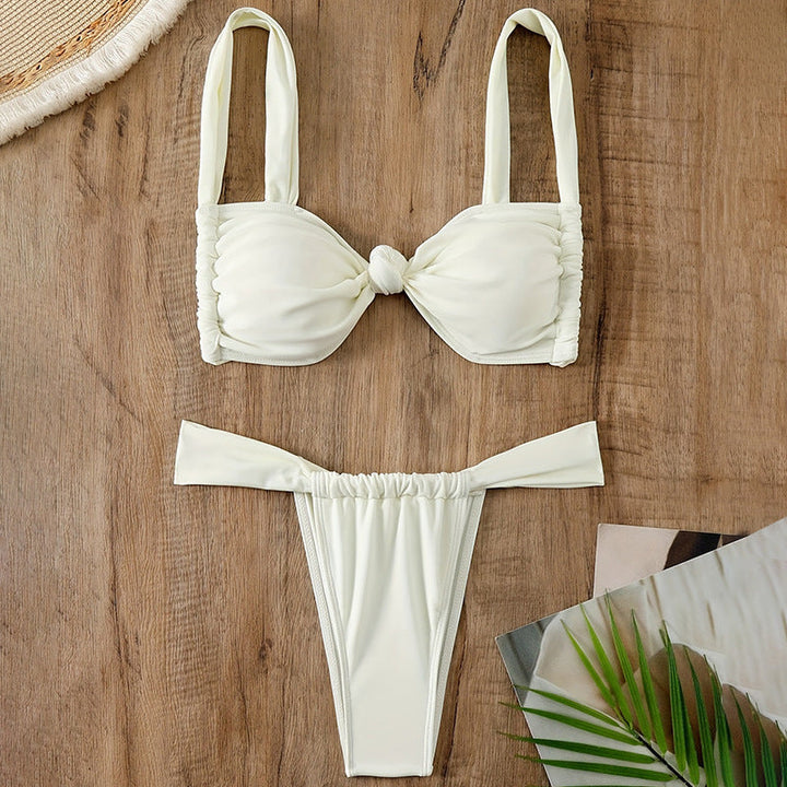 Elegant vit triangelbikini med justerbara knutar. Högt skuren ben ger en smickrande strandlook.