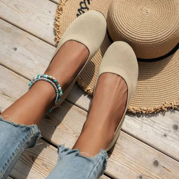 Närbild på den flexibla och halkfria EVA-sulan på vita bekväma ballerinaskor för dam.