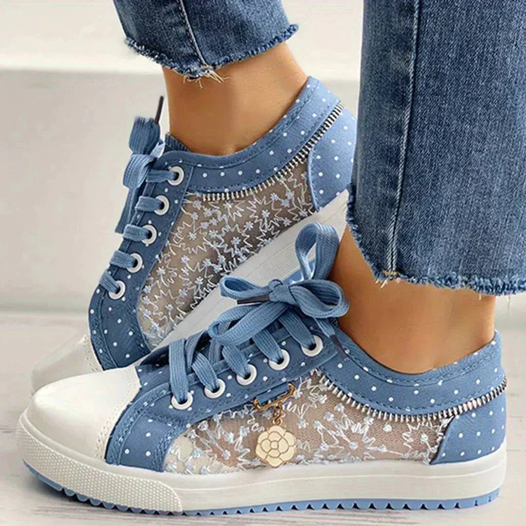Par vita damsneakers med blommig spets på vit bakgrund, framhäver lättvikt och bekväm casualstil.