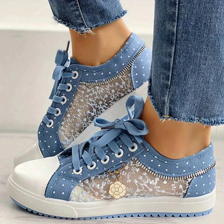 Par vita damsneakers med blommig spets på vit bakgrund, framhäver lättvikt och bekväm casualstil.