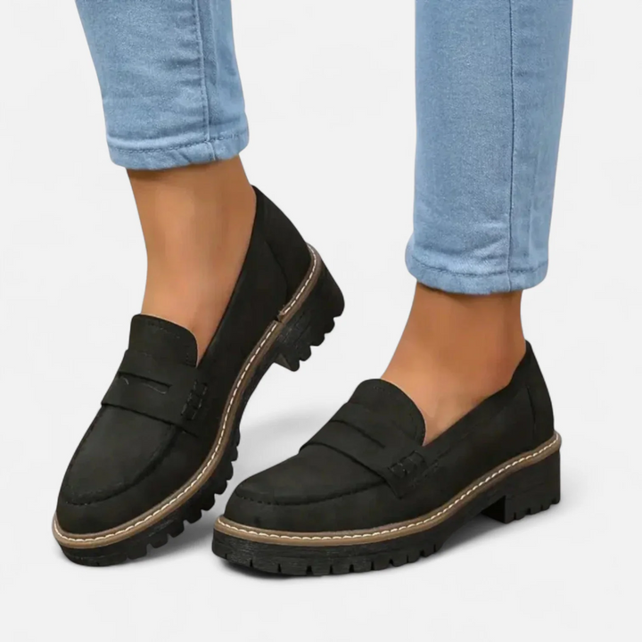 Närbild på svarta Aveline penny loafers med traktor-sula på vit bakgrund