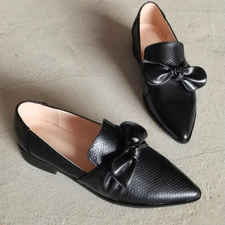 Svarta damloafers med elegant rosett och spetsig tå i närbild