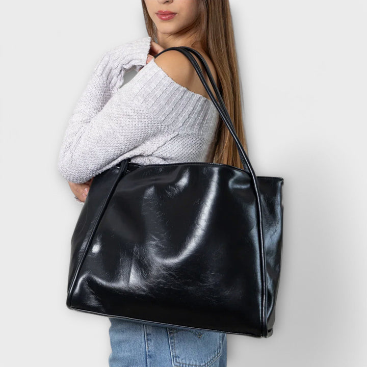 Kvinna som bär den svarta Olivia tote-väskan över axeln